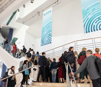 Business professionals on modern white staircase with metal railings at corporate event or conference venue for BMFMS ASM