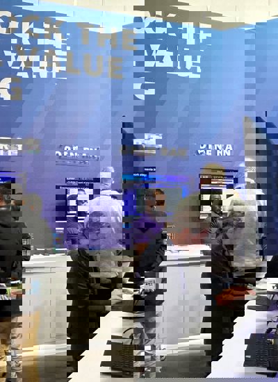 People talking at a tradeshow booth with a sign reading unlock the power of 5G