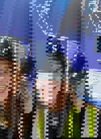 Two women wearing hard hats standing in a half built tradeshow booth