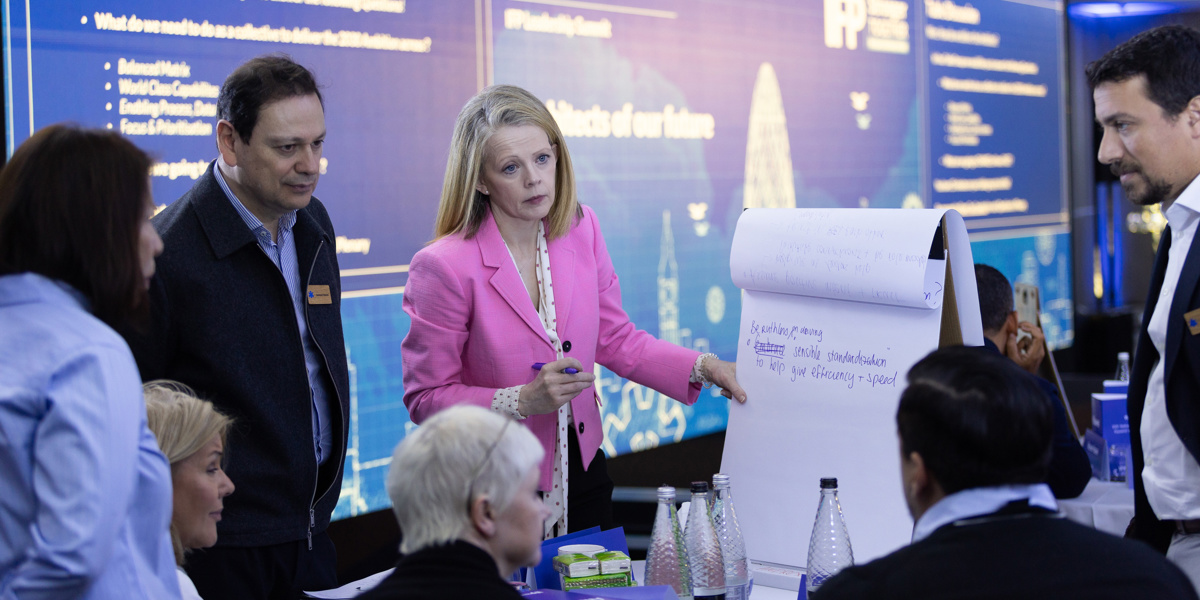 Delegates conversing and writing ideas on whiteboard at the event