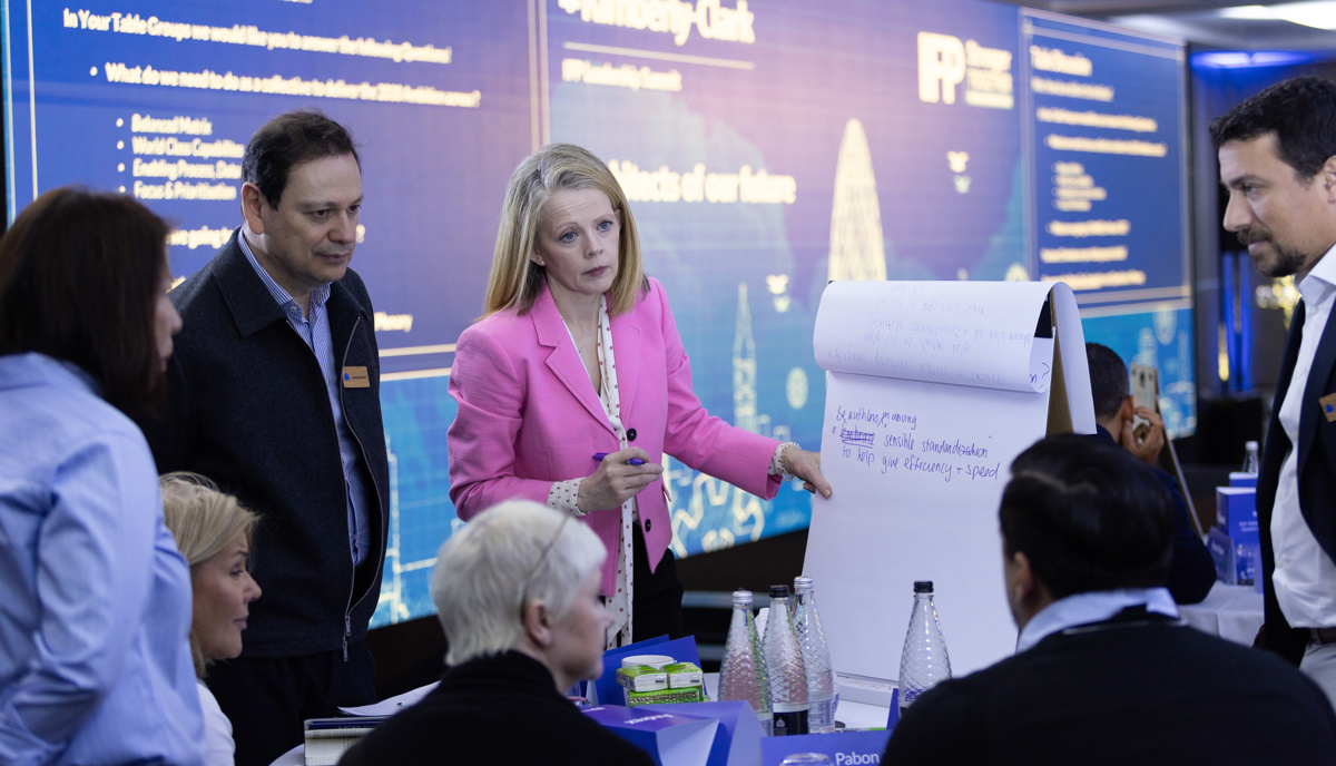 Delegates conversing and writing ideas on whiteboard at the event