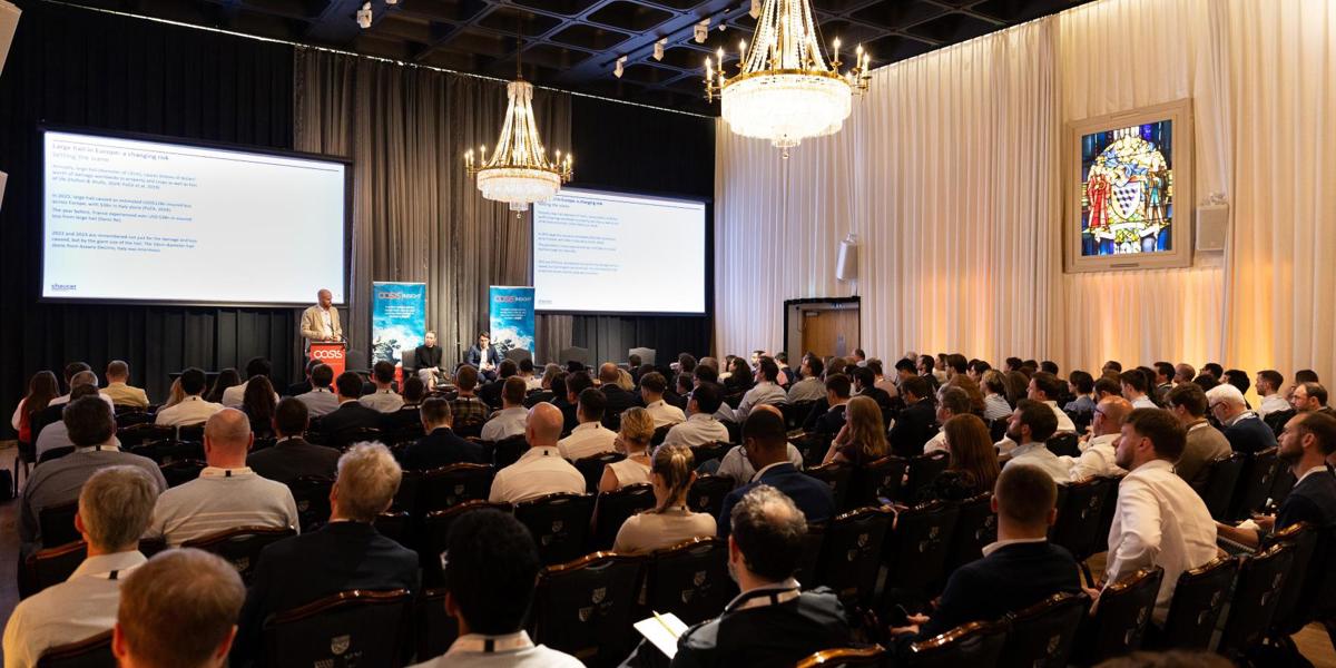 Conference audience in elegant hall with chandeliers listening to speaker at podium