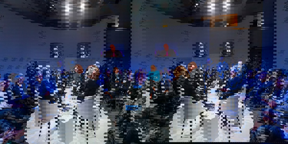 Round table discussion with speakers at the center and audience seated around them in a circle