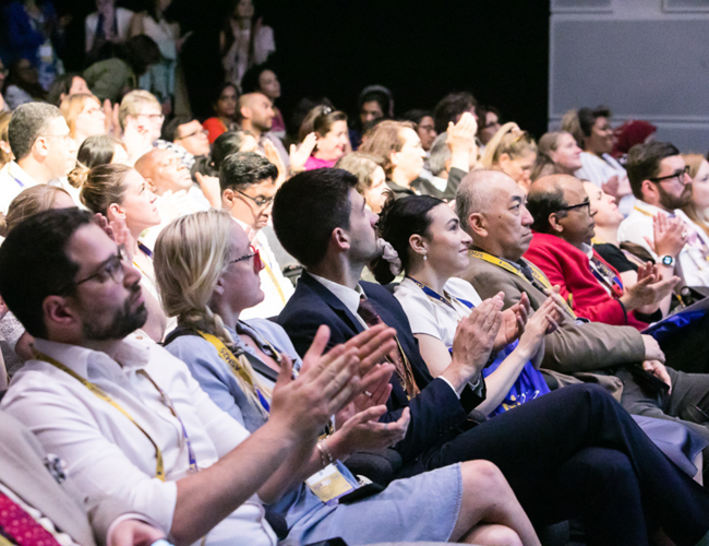 People seated and clapping during a presentation