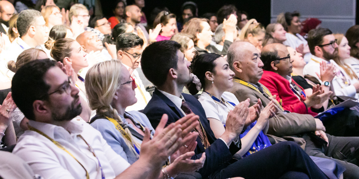 People seated and clapping during a presentation