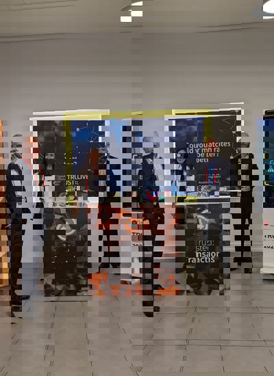 Three people standing next to a tradeshow booth called Trusted Transactions