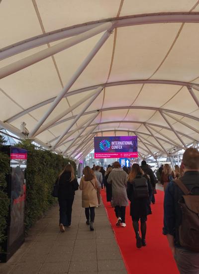 Delegates walking down a red carpet towards a large LED sign with International Confex 