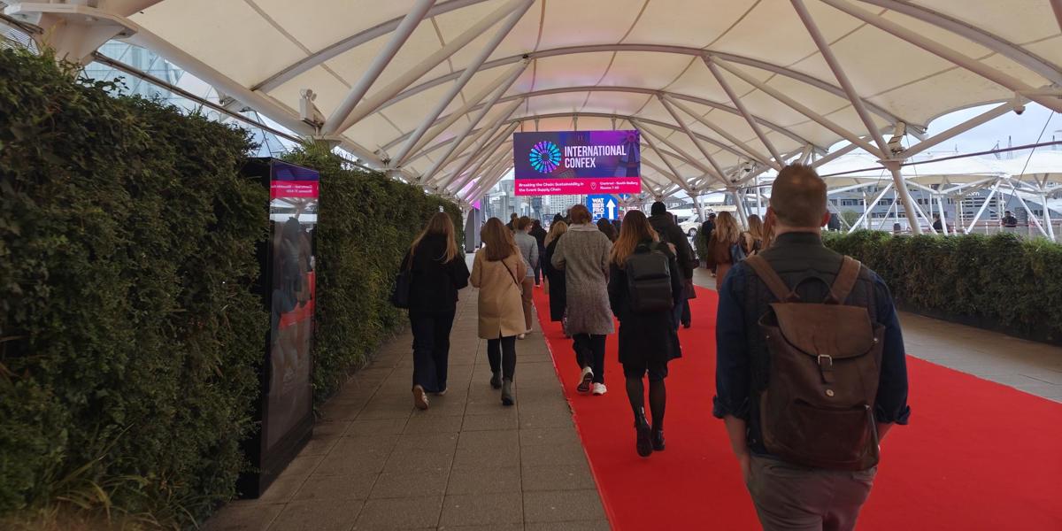 Delegates walking down a red carpet towards a large LED sign with International Confex 