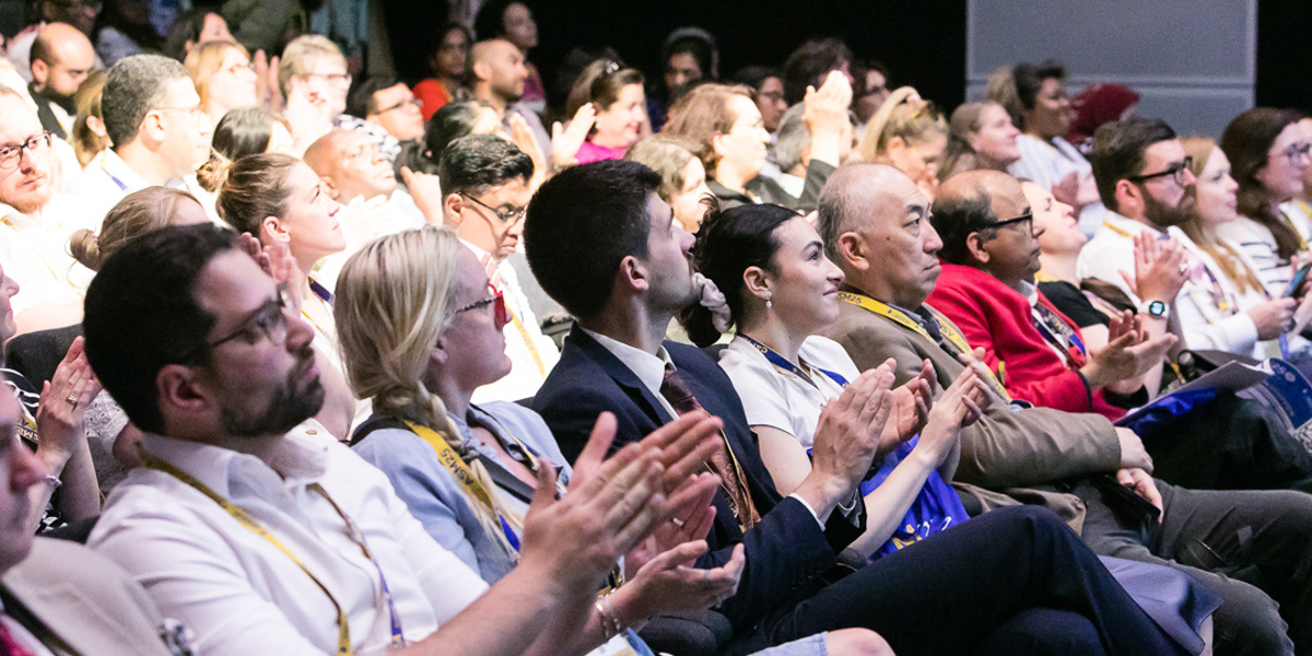 Audience of people clapping and smiling during a live event
