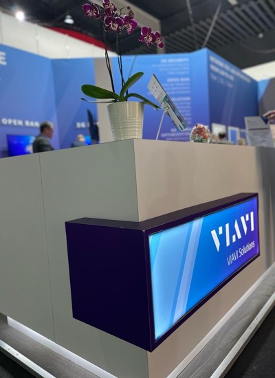A tradeshow booth displaying the VIAVI brand with a potted plant on the desk