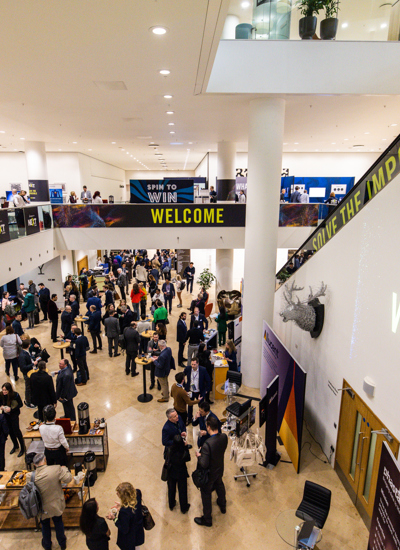 The entrance lobby of a conference centre with lots of people standing on two levels