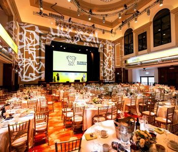 Banqueting hall set for a 300-guest AI technology awards dinner in London, with round tables, stage and screens