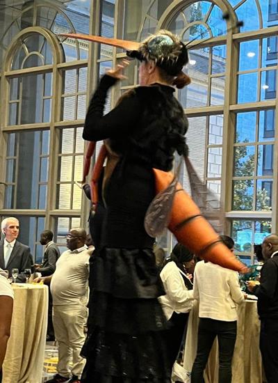 A person dressed as a giant mosquito in a room full of people standing at drinks tables