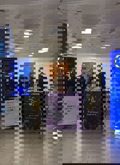 Three people standing next to a tradeshow booth called Trusted Experiences