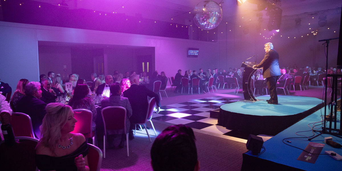 Party with dance floor and lights, delegates seated at tables and the speaker addressing them