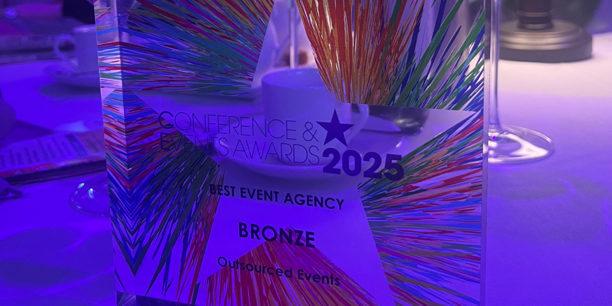 Outsourced Events wins Bronze Best Event Agency 2025 award at Conference and Events Awards, plaque on table with wine glasses.